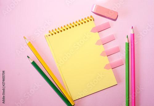 Blank notebook with colored pencils against pink pastel background. Flat lay, top view