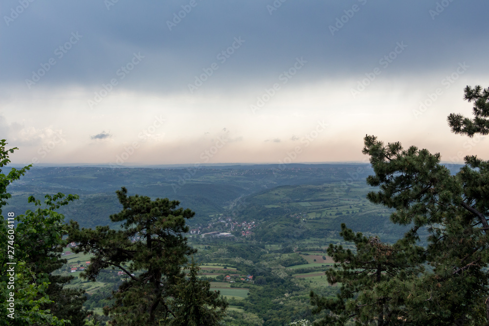 Panorama view over the lush green hills and some villages on the outskirts of Belgrade, Serbia. Moody sky. Nature scenery. Nature background.