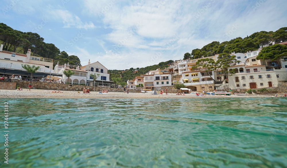 Fototapeta premium Beach shore in a peaceful Mediterranean village on the Costa Brava in Spain, seen from water surface, Sa Tuna, Begur, Catalonia