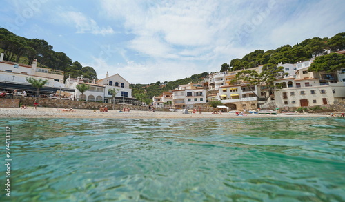 Fototapeta Naklejka Na Ścianę i Meble -  Beach shore in a peaceful Mediterranean village on the Costa Brava in Spain, seen from water surface, Sa Tuna, Begur, Catalonia