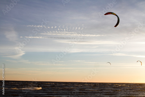 Parachutes for kitesurfing fly in the blue sky at sunset