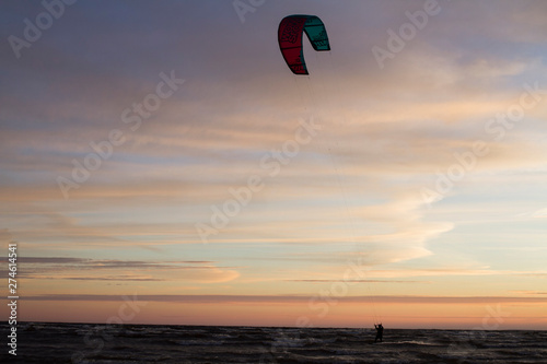 Parachutes for kitesurfing fly in the blue sky at sunset