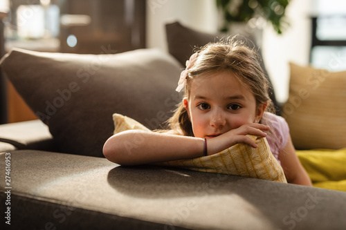 Pensive little girl relaxing on the sofa in the living room.