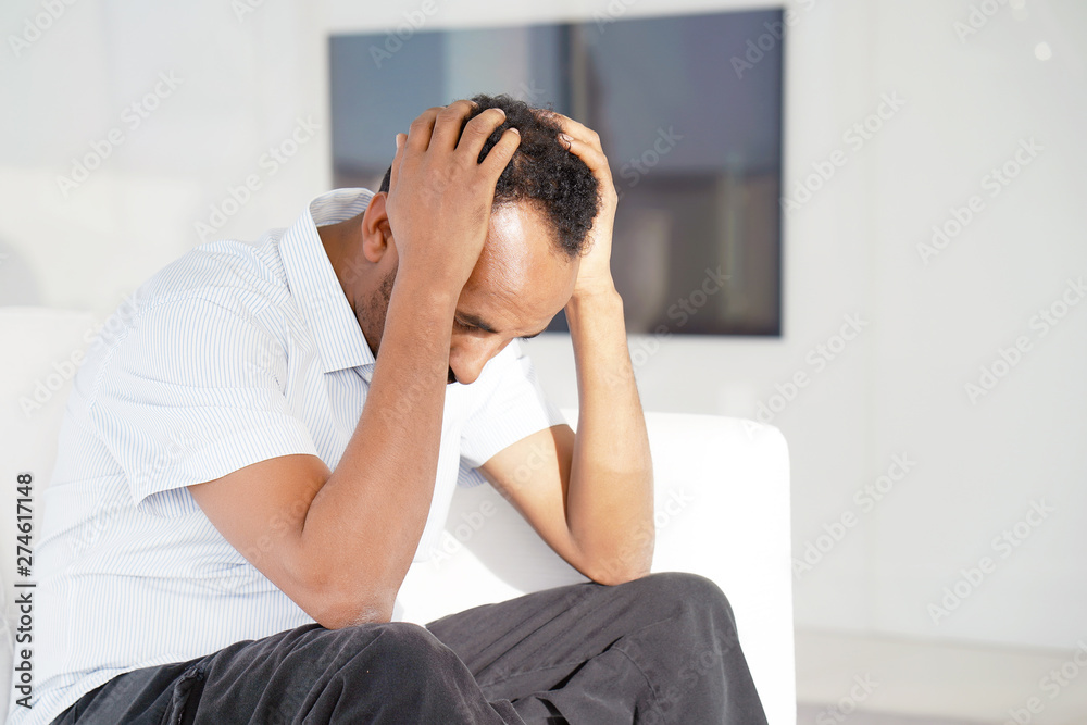 Portrait of a sad male close-up. Lonely african man is sad sitting on the bed at home. Man feel depression. Portrait of a sad male close-up. Lonely african man is sad sitting on the bed at home. Man feel depression.