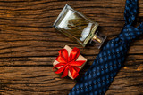 Blue tie, perfume and box and gift on antique wooden background.