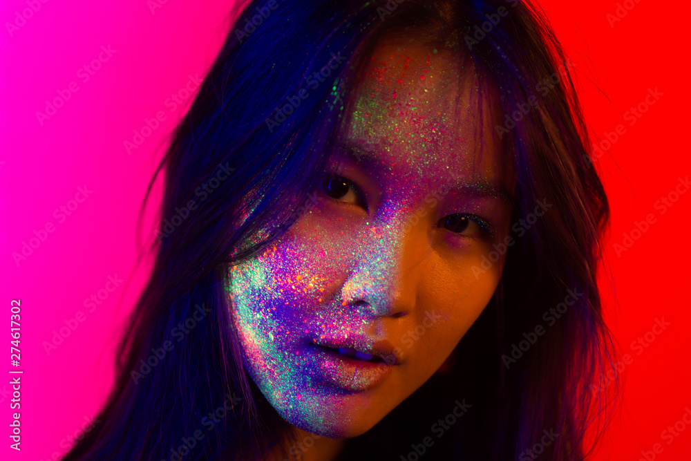 Beautiful young woman dancing and making party with fluorescent painting on her face. Neon facial portraits Beautiful young woman dancing and making party with fluorescent painting on her face. Neon facial portraits