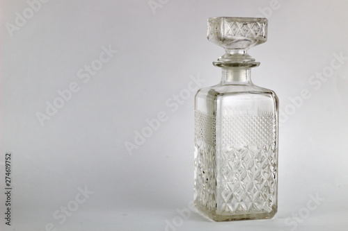 Glass bottle of square shape on a light background.