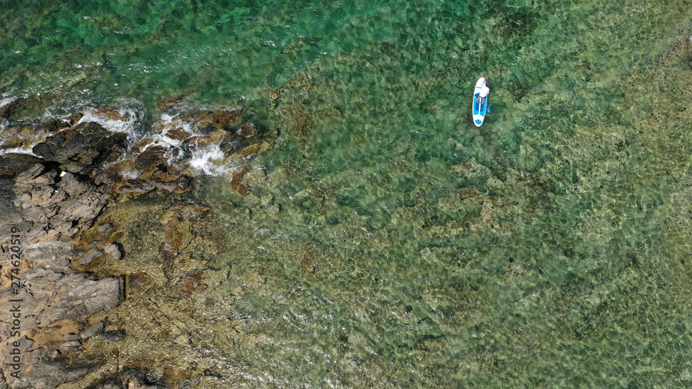 Aerial photo of unidentified fit man practising SUP or Stand Up Paddle in tropical exotic destination island with turquoise sea Aerial photo of unidentified fit man practising SUP or Stand Up Paddle in tropical exotic destination island with turquoise sea