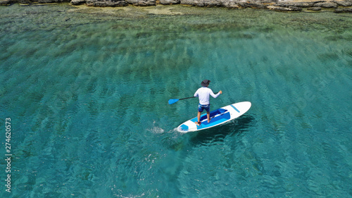 Aerial photo of unidentified fit man practising SUP or Stand Up Paddle in tropical exotic destination island with turquoise sea © aerial-drone