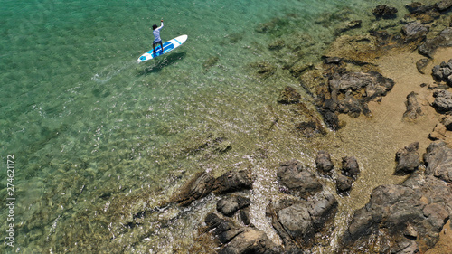 Aerial drone photo of unidentified fit man practising Stand Up Paddle or SUP in tropical exotic mediterranean bay with turquoise sea