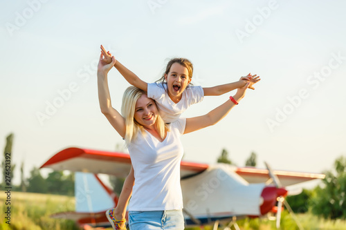 happy family at sunset. mother and her child daughter looking at the flying plane in the sky