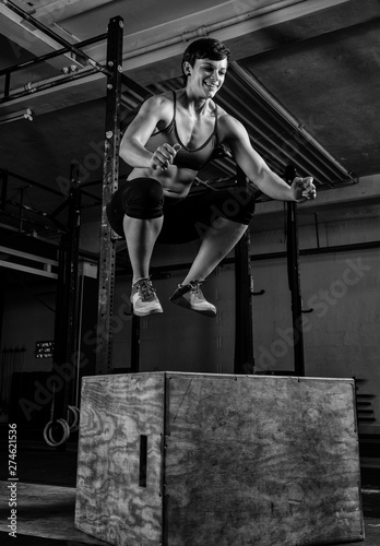 Junge athletische Frau beim Workout. Die h  bsche muskul  se Sportlerin macht Box Jumps im Krafttraining. Schwarz und wei   Portr  t.