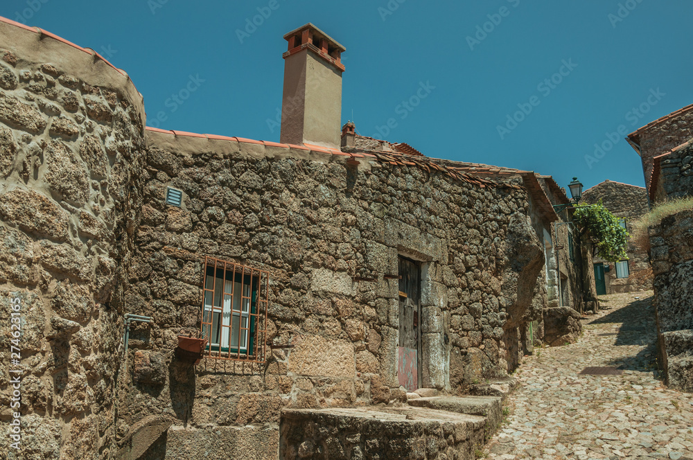 Old houses with stone wall in alley on slope at Monsanto