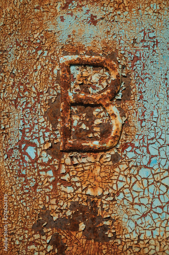 Rusted metal with cracks, peeling paint and the B letter