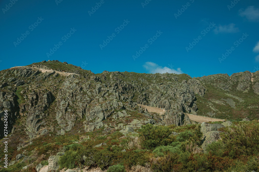 Retaining wall of road passing through rocky landscape