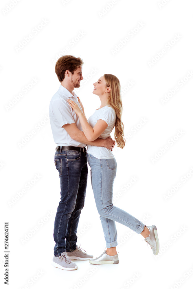 Beautiful young couple in casual clothing flirting, white background