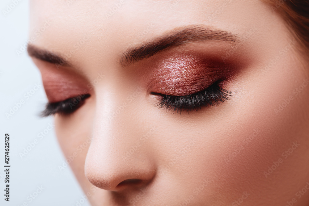 Close up view of blue woman eye with beautiful golden shades and black eyeliner makeup. Classic make up. Perfect brows. Studio shot