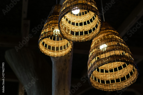 Handcraft lamp with weave pattern hanging from dark ceiling. Traditional handcraft made from wooden vine widely used for interior decoration and furniture.