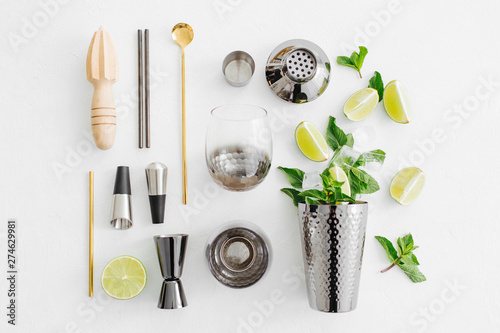 Set of bar accessories for cocktail making. Shaker, jigger, glass, spoon  and  other bar tools with lime and mint leaves on withe  background. photo