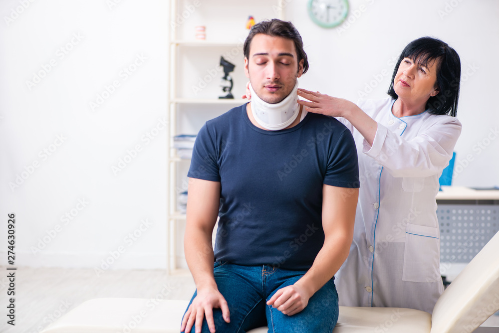 Young male patient visiting aged female doctor Young male patient visiting aged female doctor