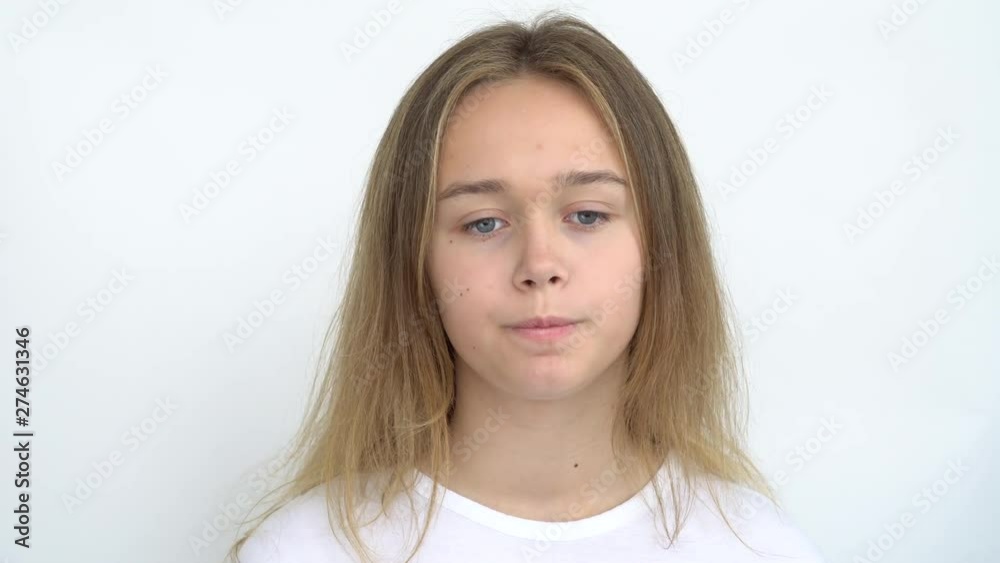 Portrait of a teenage girl with long flowing hair on a white background who stands thoughtfully and licks her lips . Close up. Portrait of a teenage girl with long flowing hair on a white background who stands thoughtfully and licks her lips . Close up.
