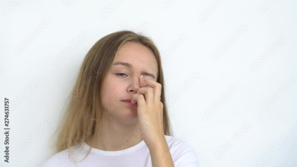 Portrait of a teenage girl with long flowing hair on a white background that straightens her hair and removes an eyelash caught under her eyelid. Close up. Portrait of a teenage girl with long flowing hair on a white background that straightens her hair and removes an eyelash caught under her eyelid. Close up.