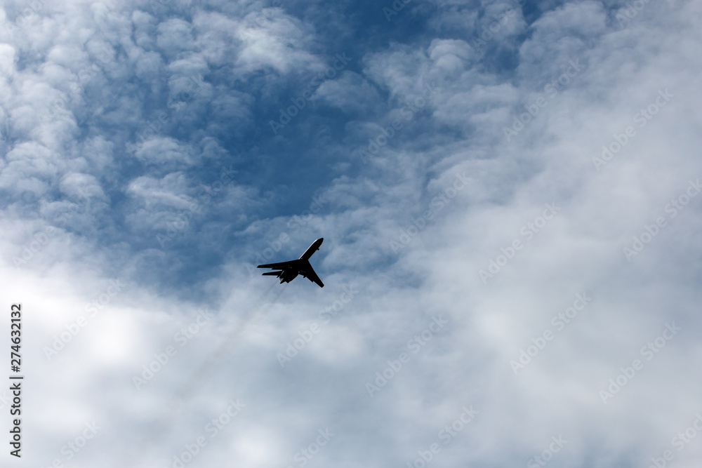 the plane flies across the blue sky