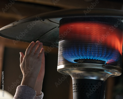 Hands warming close to the flames of propane patio heater