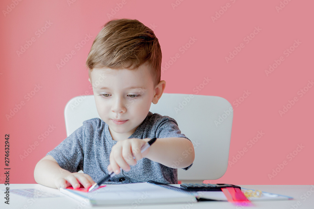 Portrait of cute kid boy at home making homework. Little concentrated child writing with colorful pencil, indoors. Elementary school and education. Kid learning writing letters and numbers Portrait of cute kid boy at home making homework. Little concentrated child writing with colorful pencil, indoors. Elementary school and education. Kid learning writing letters and numbers