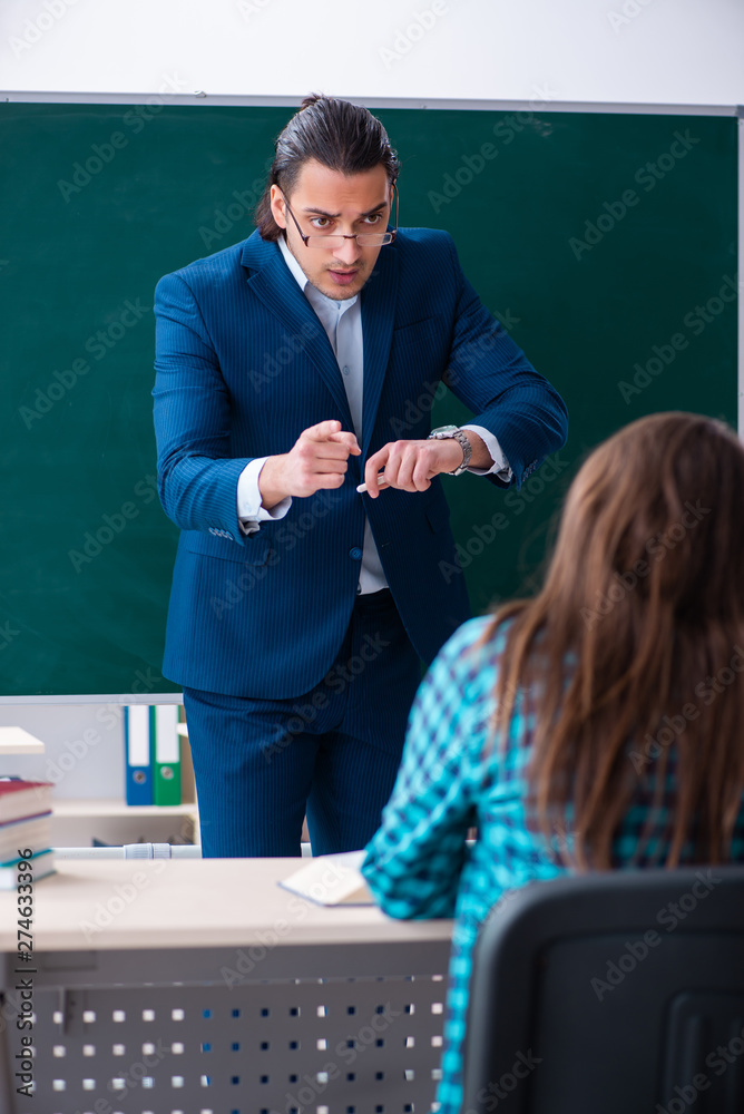 Young handsome teacher and female student in the classroom Young handsome teacher and female student in the classroom