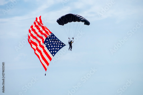 Parachute carries an American flag flying in the sky