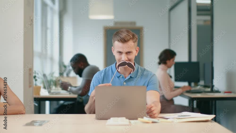 Young man working on laptop computer at coworking. Joyful man making male Young man working on laptop computer at coworking. Joyful man making male