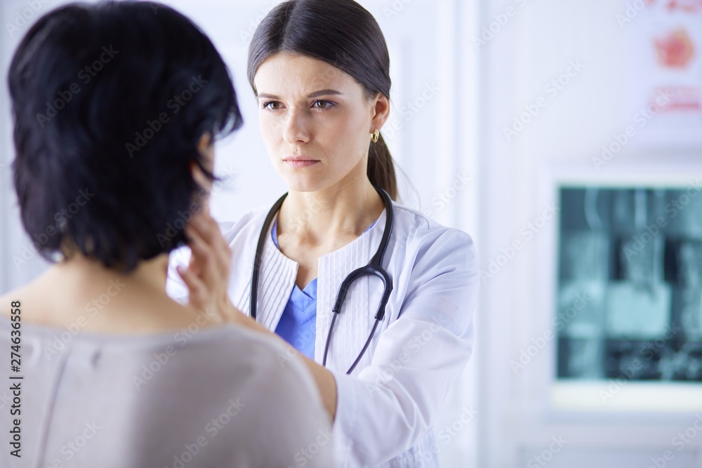 A serious female doctor examining a patient's lymph nodes A serious female doctor examining a patient's lymph nodes