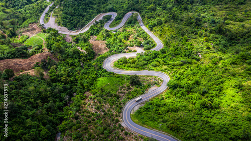 Aerial view road in mountains, Road running through green hills forest with car. © Kalyakan