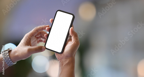 Man hands holding blank screen smartphone with blurred light bokeh background