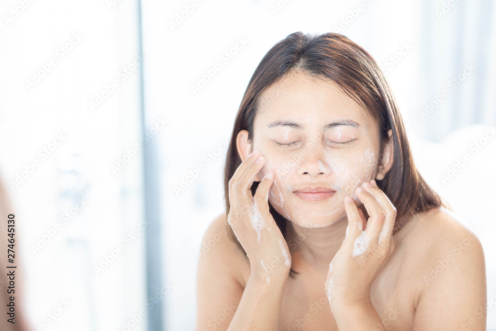 Close up woman looking reflection in the mirror for washing face with foam in the bathroom, health care and beauty concept Close up woman looking reflection in the mirror for washing face with foam in the bathroom, health care and beauty concept