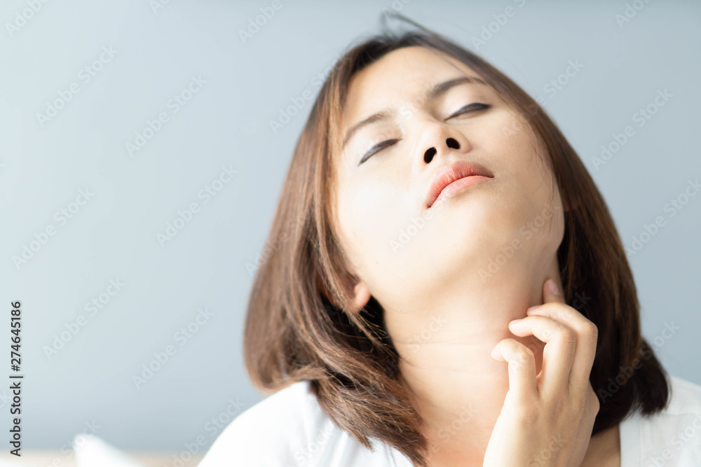 Closeup woman holding neck with pain after waking up on bed, healthy care and medical concept Closeup woman holding neck with pain after waking up on bed, healthy care and medical concept