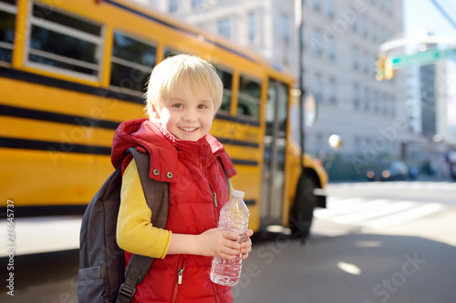 Pupil with schoolbag and bottle of water with yellow school bus on background.