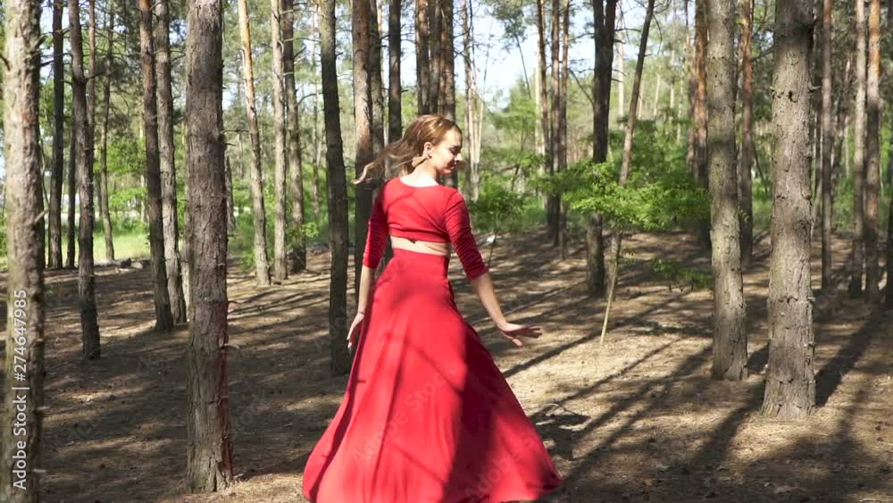 Contemporary skill woman dancer in red dress dancing in forest. Improvisation. Look at camera Contemporary skill woman dancer in red dress dancing in forest. Improvisation. Look at camera