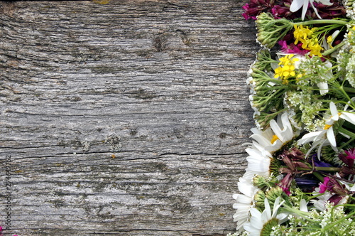 A bouquet of wildflowers lies on a wooden table in the form of a frame