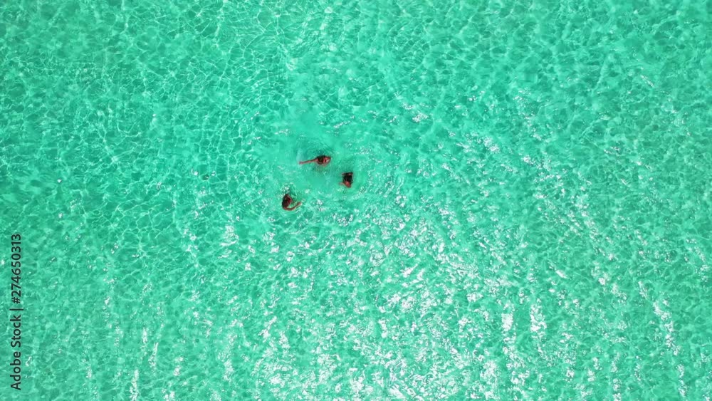 young attractive women having fun, dancing and splashing water in the crystal clear sea on exotic island, Thailand, aerial drone high angle shot young attractive women having fun, dancing and splashing water in the crystal clear sea on exotic island, Thailand, aerial drone high angle shot