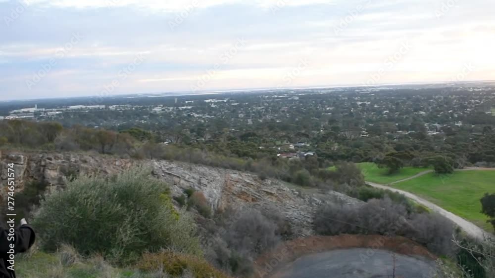 Caucasian young adult woman standing on a cliff side, watching the landscape while holding a smartphone Caucasian young adult woman standing on a cliff side, watching the landscape while holding a smartphone