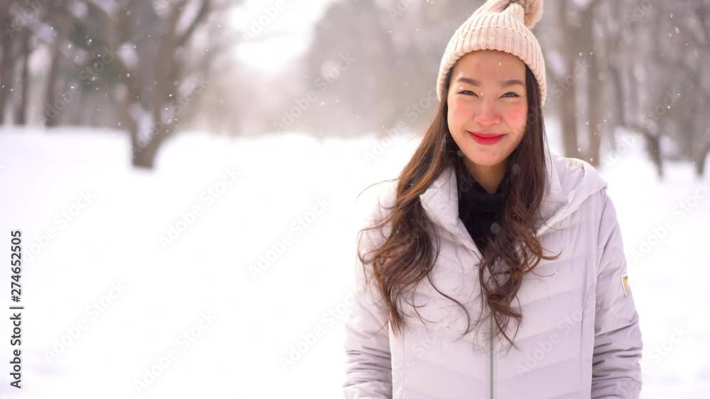 A handheld shot of a woman facing the camera and smiling. Shot is in a snow covered forested area in Hokkaido, Japan. A handheld shot of a woman facing the camera and smiling. Shot is in a snow covered forested area in Hokkaido, Japan.