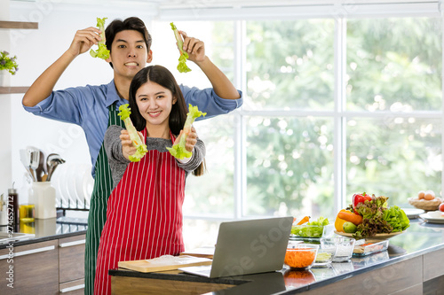 Couple in apron make salad rolls together..