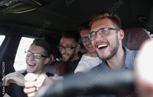 Group of happy friends on a car. Focus on the man