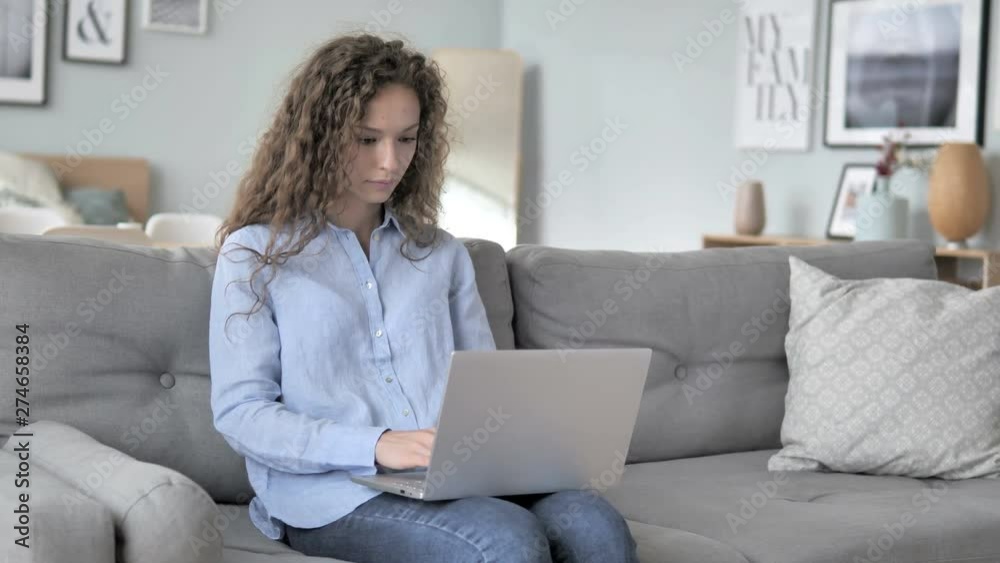 Curly Hair Woman Working On Laptop while Sitting on Couch Curly Hair Woman Working On Laptop while Sitting on Couch
