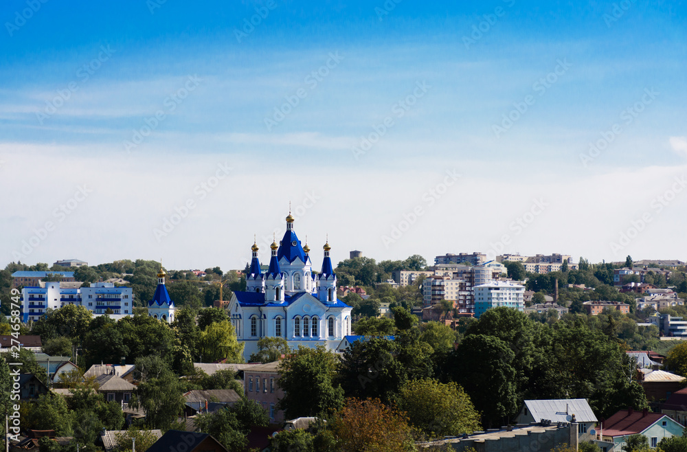 Panoramic view of the city, white and blue church in city on sky background
