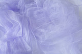 Textile and textural concept - close up of a crumpled veil of lilac wavy fabric background with copy space for text or image