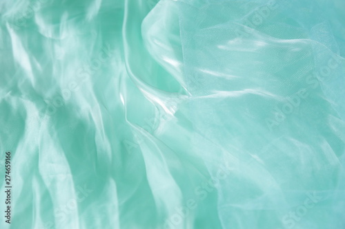 Textile and texture concept - close up of crumpled silk turquoise wavy fabric background with copy space for text or image