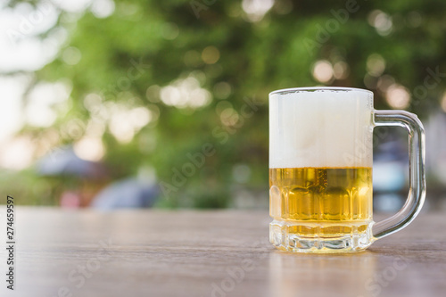 Beer in glass on wooden table with natural background with bokeh